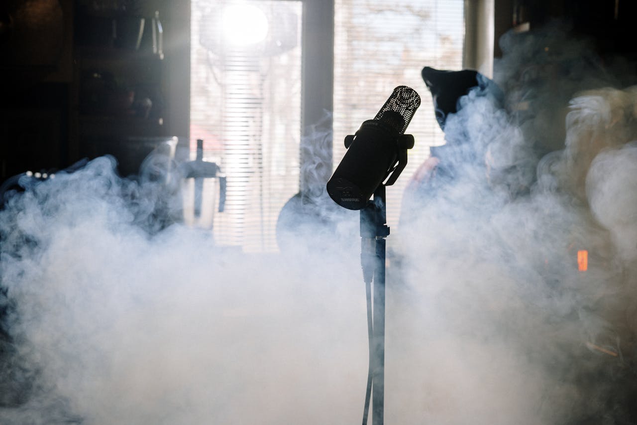 menu-04 A mysterious microphone stands amidst swirling smoke in a sunlit home studio.