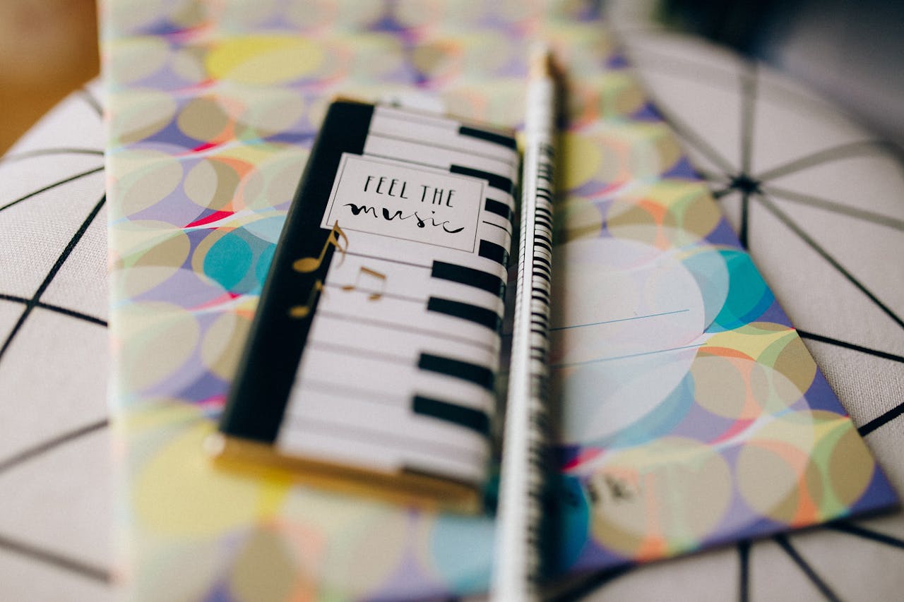 menu-15 A vibrant close-up of a notebook with keyboard design and pencil, perfect for music enthusiasts.