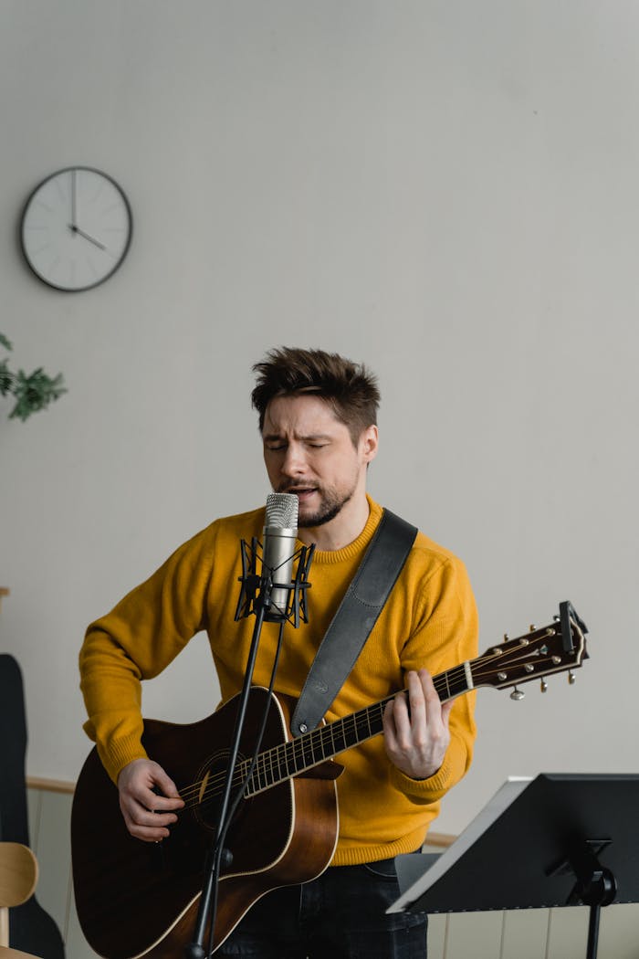 Male musician passionately sings and plays acoustic guitar in a cozy room.
