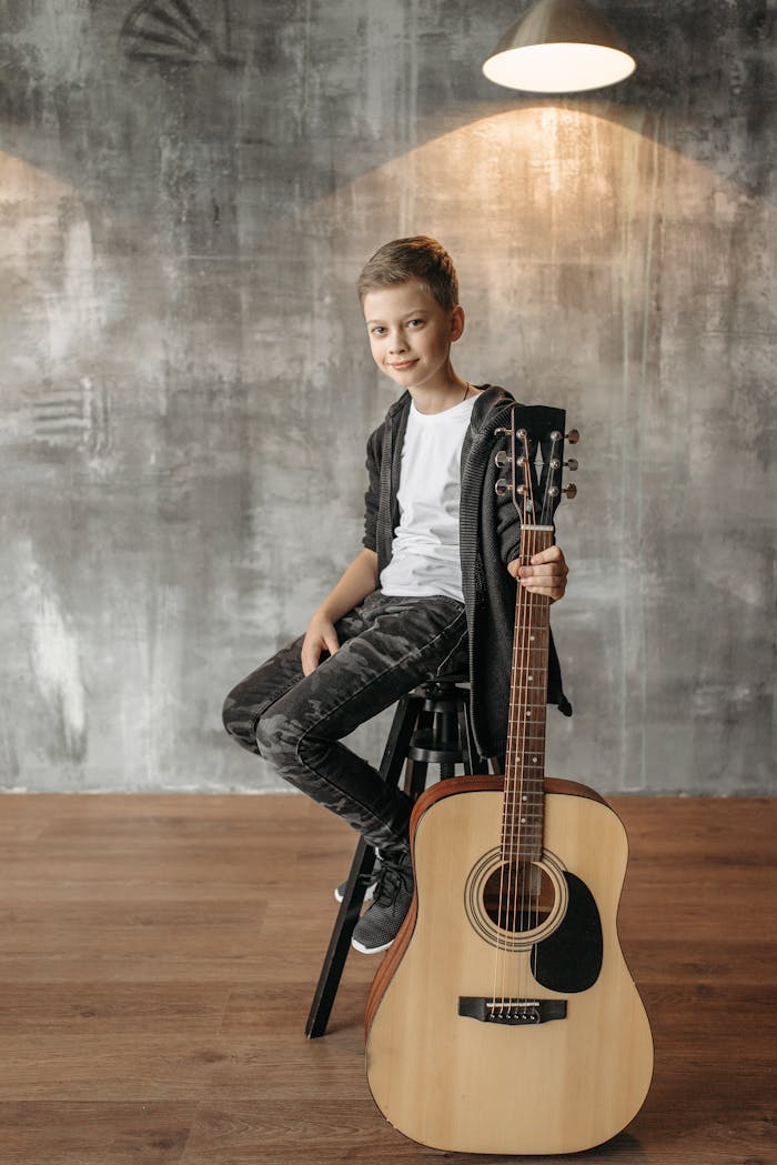 A young boy sitting with an acoustic guitar, creating a warm and musical atmosphere indoors.
