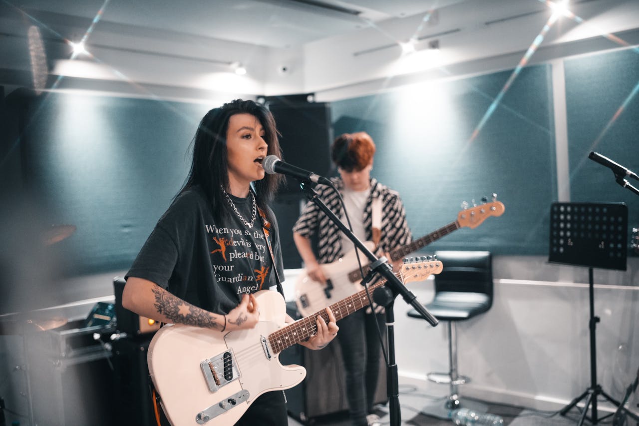 menu-07 Female musician performs with electric guitar and microphone in a studio setting.